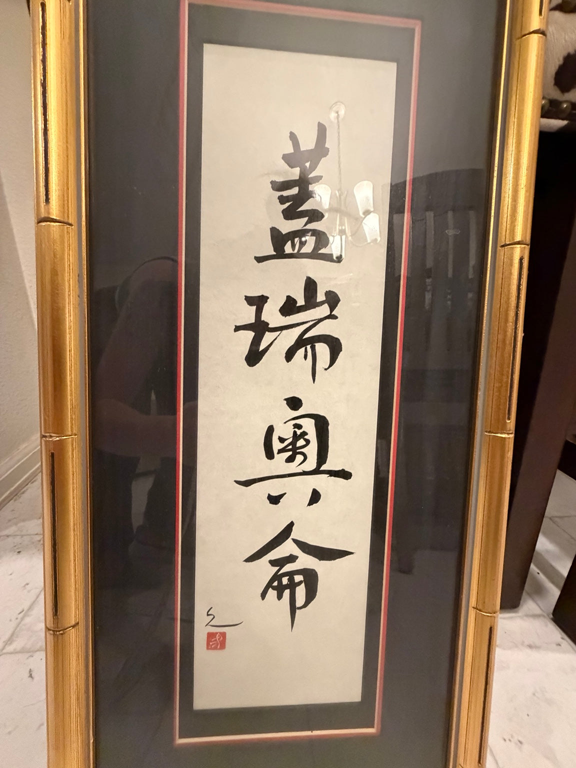 Close view of four black calligraphy characters on cream-colored paper behind glass